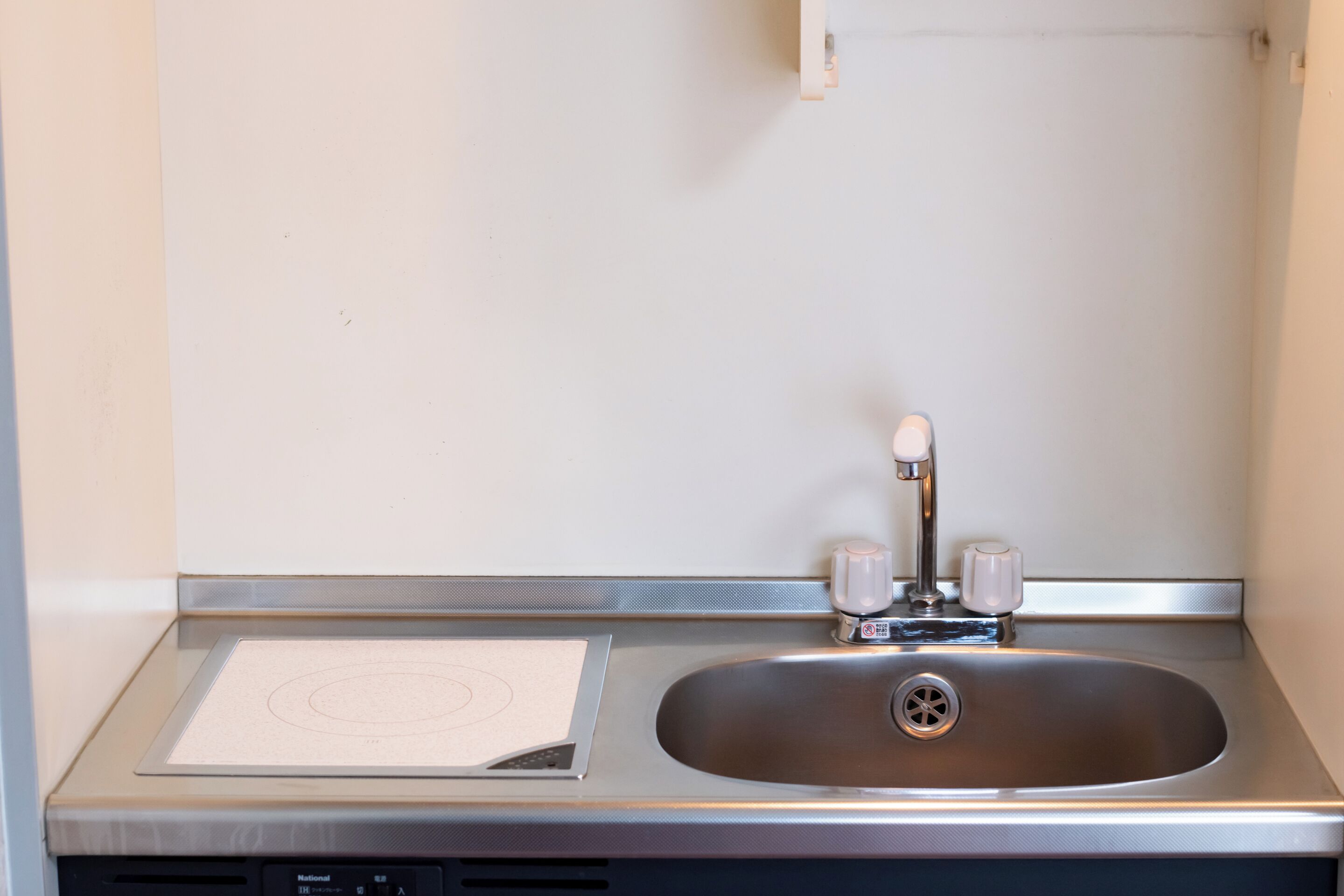 A stainless steel sink with a single faucet and a paper towel dispenser.