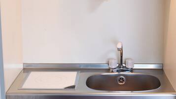 A stainless steel sink with a single faucet and a paper towel dispenser.