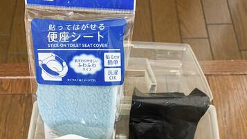 A plastic container with a blue label and two white toilet seat covers.