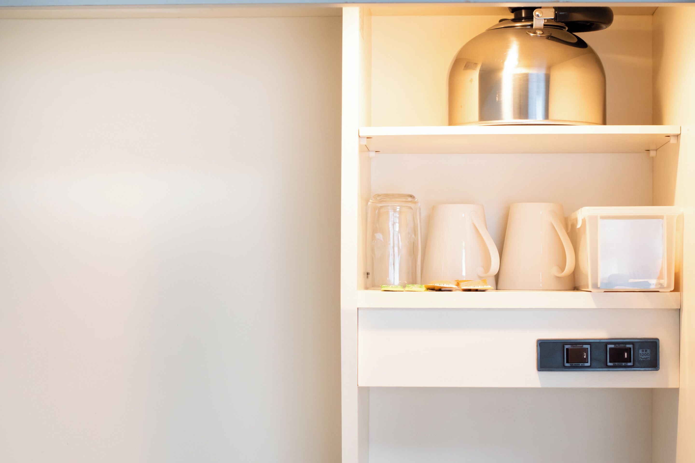 Una cocina con tetera, cafetera y microondas sobre la encimera.