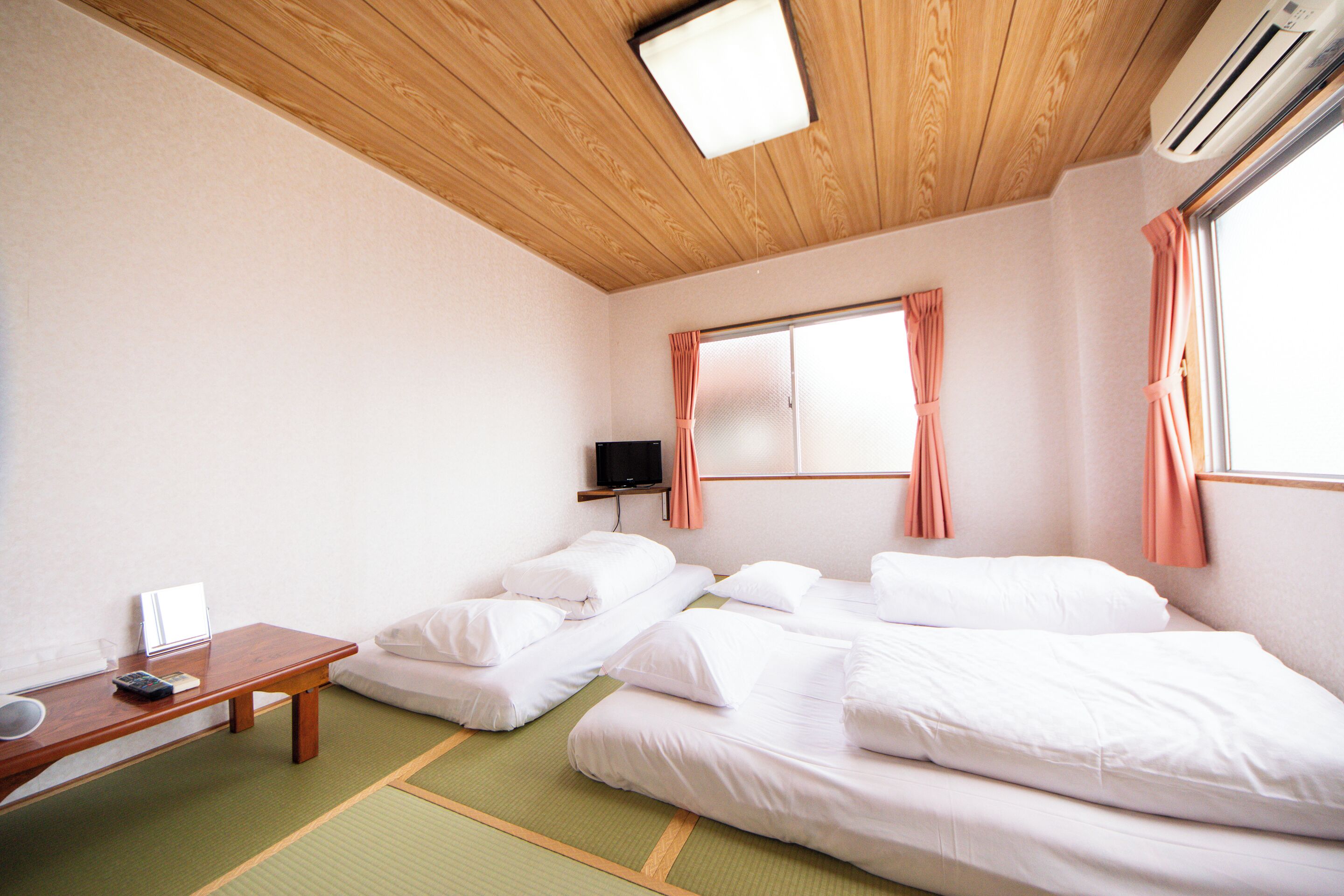 Una habitación con dos camas, una mesita, un televisor y un equipo de aire acondicionado.