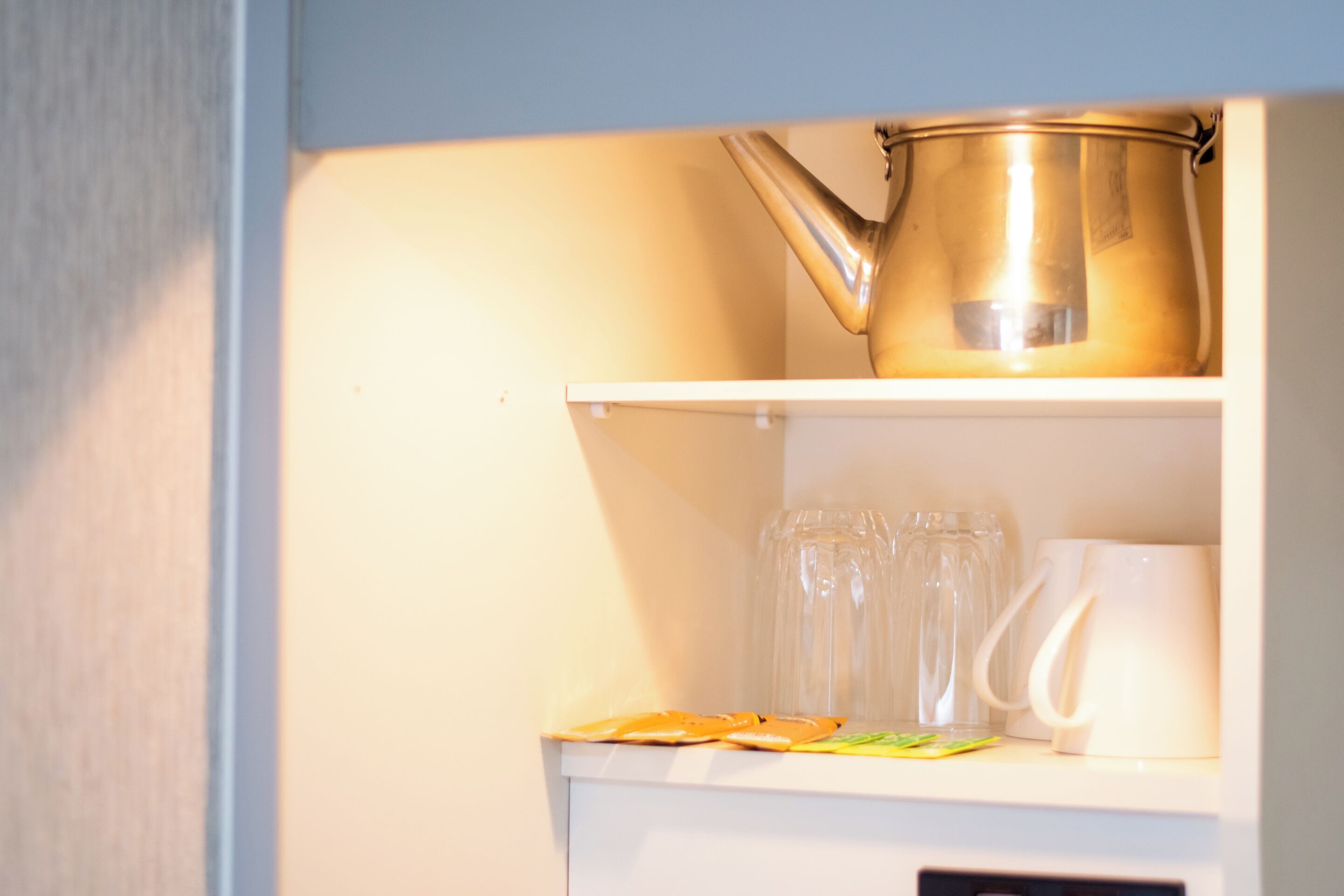 Une étagère de cuisine avec une bouilloire, des verres et une tasse.