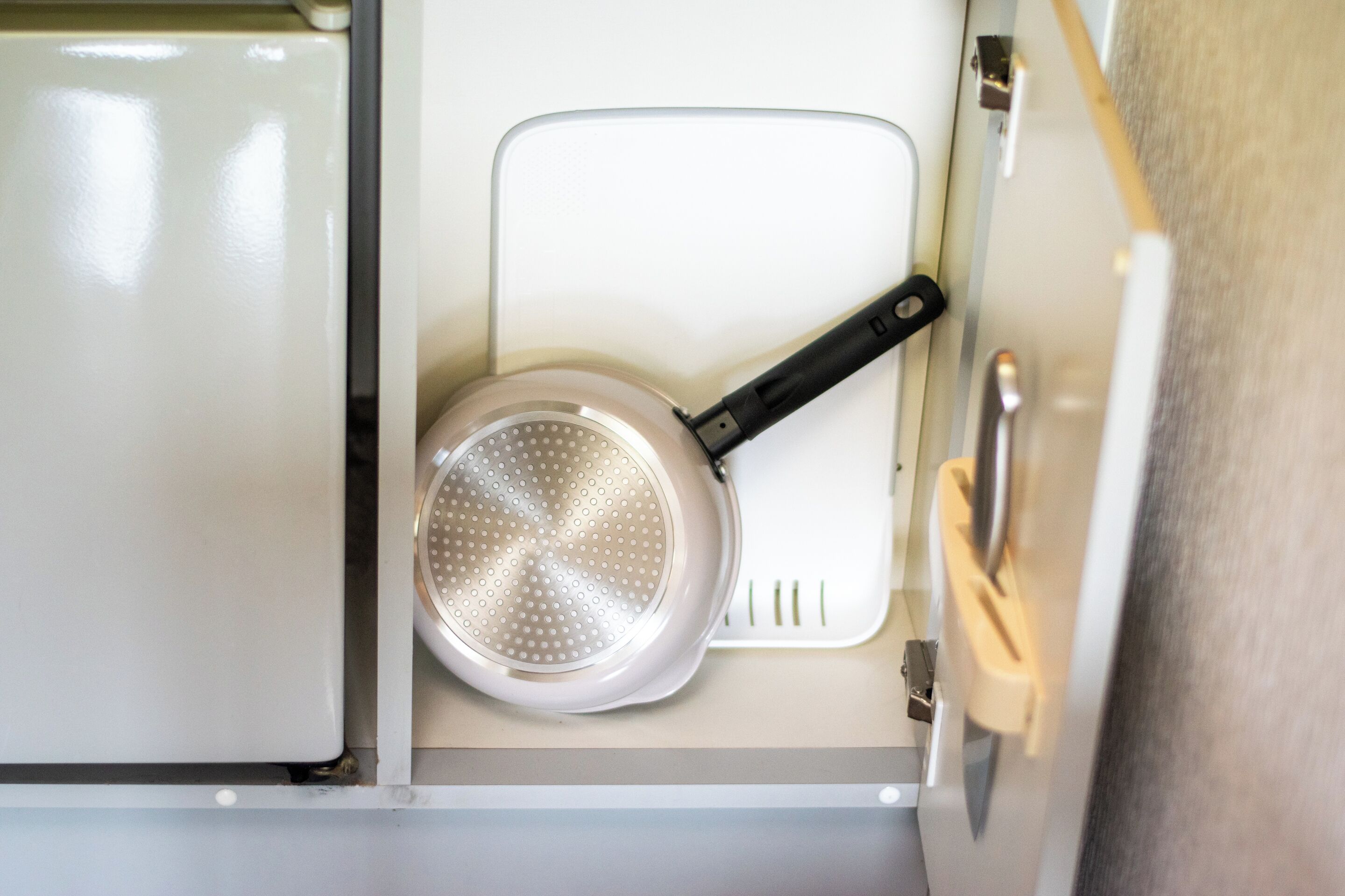 A kitchen with a white countertop, a stainless steel pan, and a white appliance.