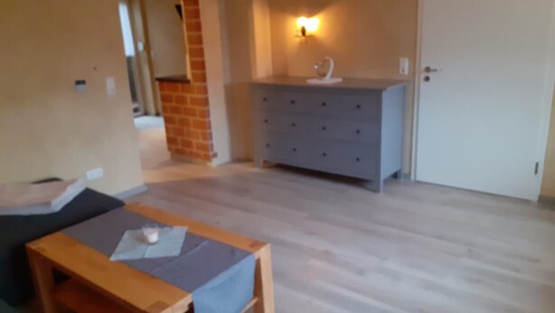 Une pièce comprenant un banc en bois, une commode et un luminaire fixé au mur.