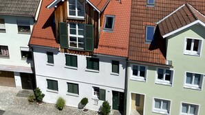Ein mehrstöckiges Gebäude mit rotem Ziegeldach, einem Balkon und Blick auf einen See.