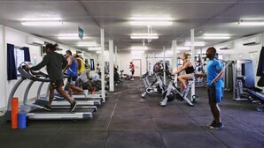 Un gimnasio con cintas de correr, bicicletas estáticas y máquinas de pesas.