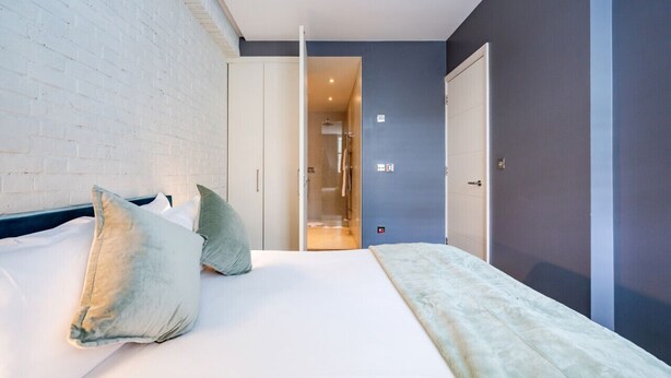 Un dormitorio moderno con cama, almohadas y un armario.