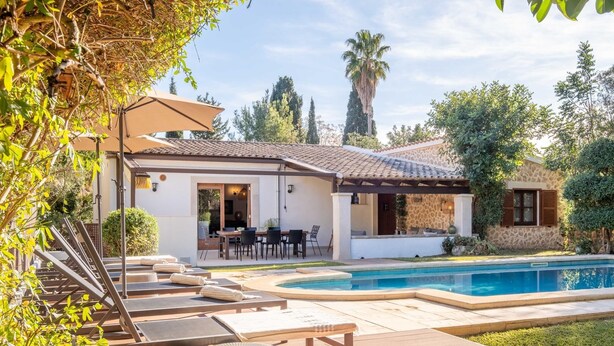 Une maison avec une piscine, un espace salon extérieur et un patio.
