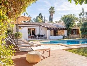Une maison avec une piscine, un espace salon extérieur et un patio.