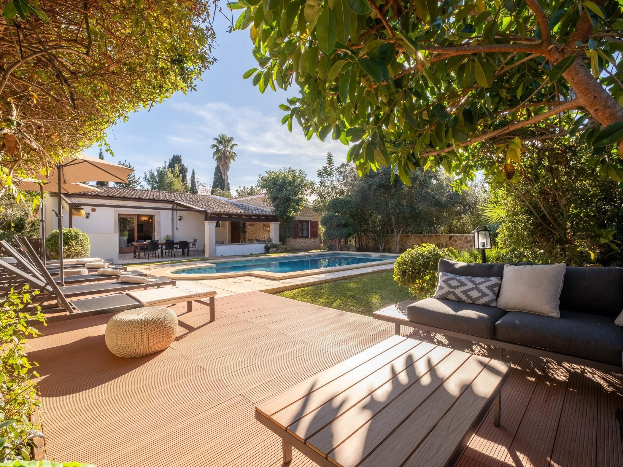 A poolside area with a wooden deck, a sofa, and a dining area with outdoor furniture.