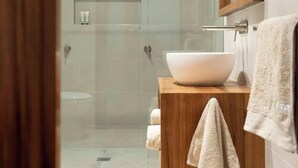 A modern bathroom with a glass shower enclosure, a wooden vanity, and a large mirror.