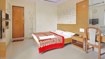 A hotel room with a bed, bedside table, chair, and a mirror.