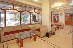 A hotel lobby with a sofa, chairs, a glass coffee table, and a reception desk. - Hotel Raipur Pride - Raipur (Raipur)