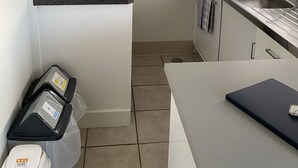 A compact kitchen with a built-in stove, a sink, and a clock on the wall.