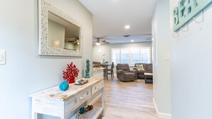 Un salon moderne avec une console blanche, un grand miroir et un ventilateur de plafond.