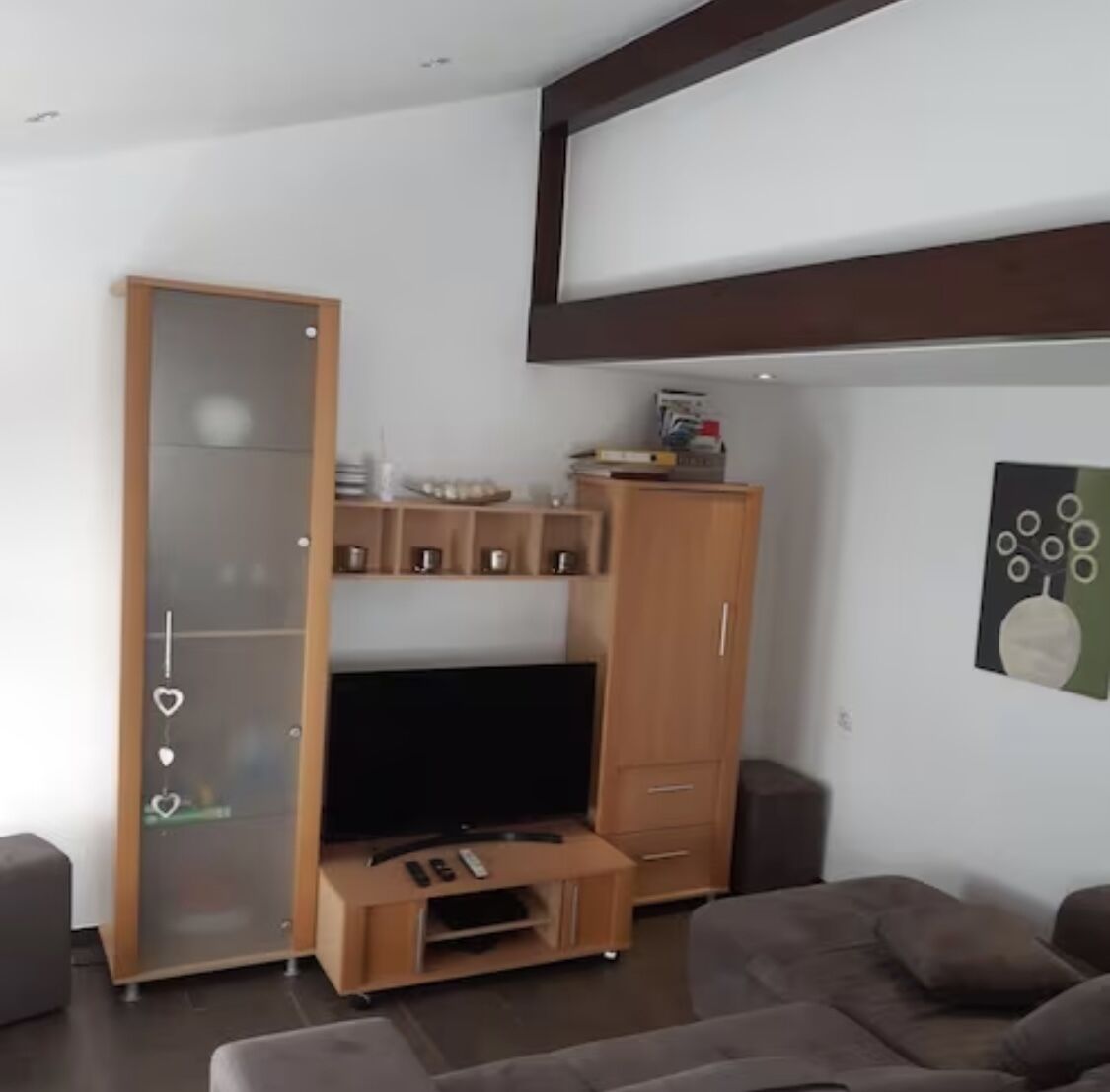 Una sala de estar moderna con un mueble de madera para entretenimiento, un televisor de pantalla plana y un sofá.