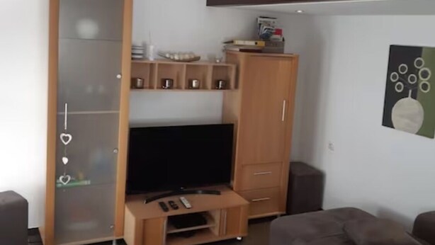 Un salon moderne avec un meuble de rangement en bois, un téléviseur à écran plat et un canapé.