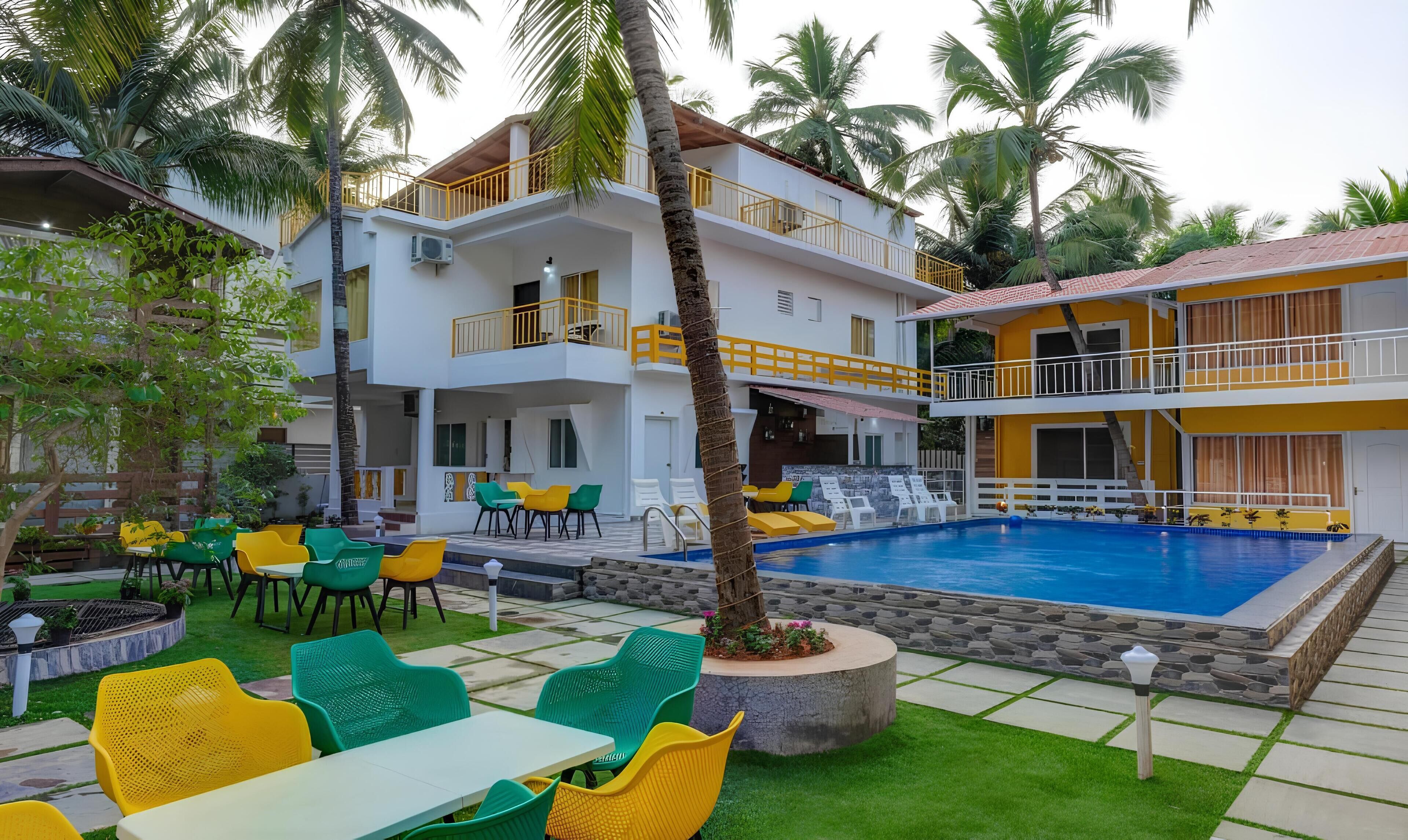 A hotel with a swimming pool, outdoor seating, and palm trees.