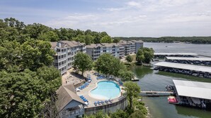 Un hôtel doté d’une piscine entourée de chaises longues, situé près d’une étendue d’eau où sont amarrés des bateaux.