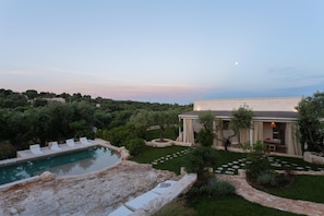A pool with lounge chairs, a garden with a stone pathway, and a building with a covered patio. - Villa Borghetto Formica (Ostuni)