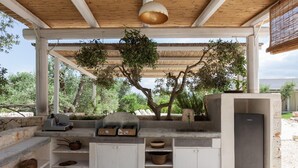 An outdoor kitchen area with a built-in grill, storage cabinets, and a refrigerator. - Villa Borghetto Formica (Ostuni)