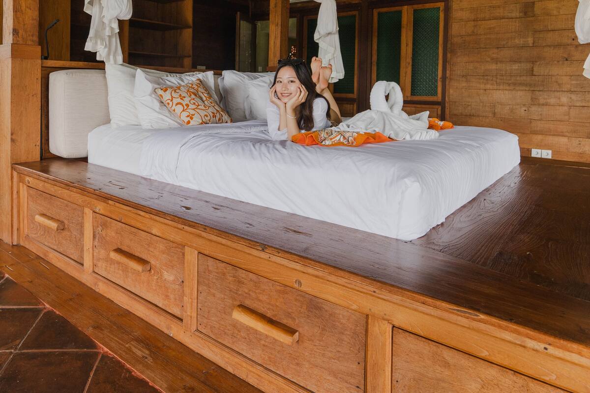 Un dormitorio estilo cabaña de madera con una cama con dosel, una mesita de noche de madera y un ventanal grande.