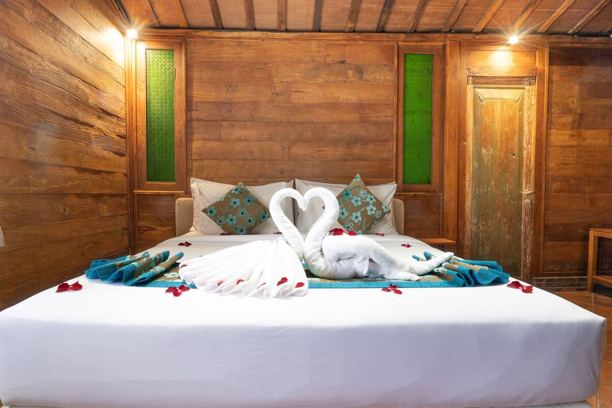 Una habitación de madera con una cama, almohadas y una decoración de toallas con forma de corazón.