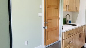 A modern kitchen with a large wooden door, a built-in sink, and wooden cabinets. - Comfortable lodging close to Whitewater & town (Nelson)