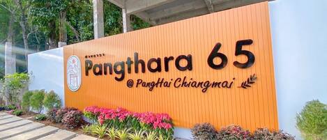 A building entrance with a sign reading "Pangthara 65 @ Pangthai Chiangmai".