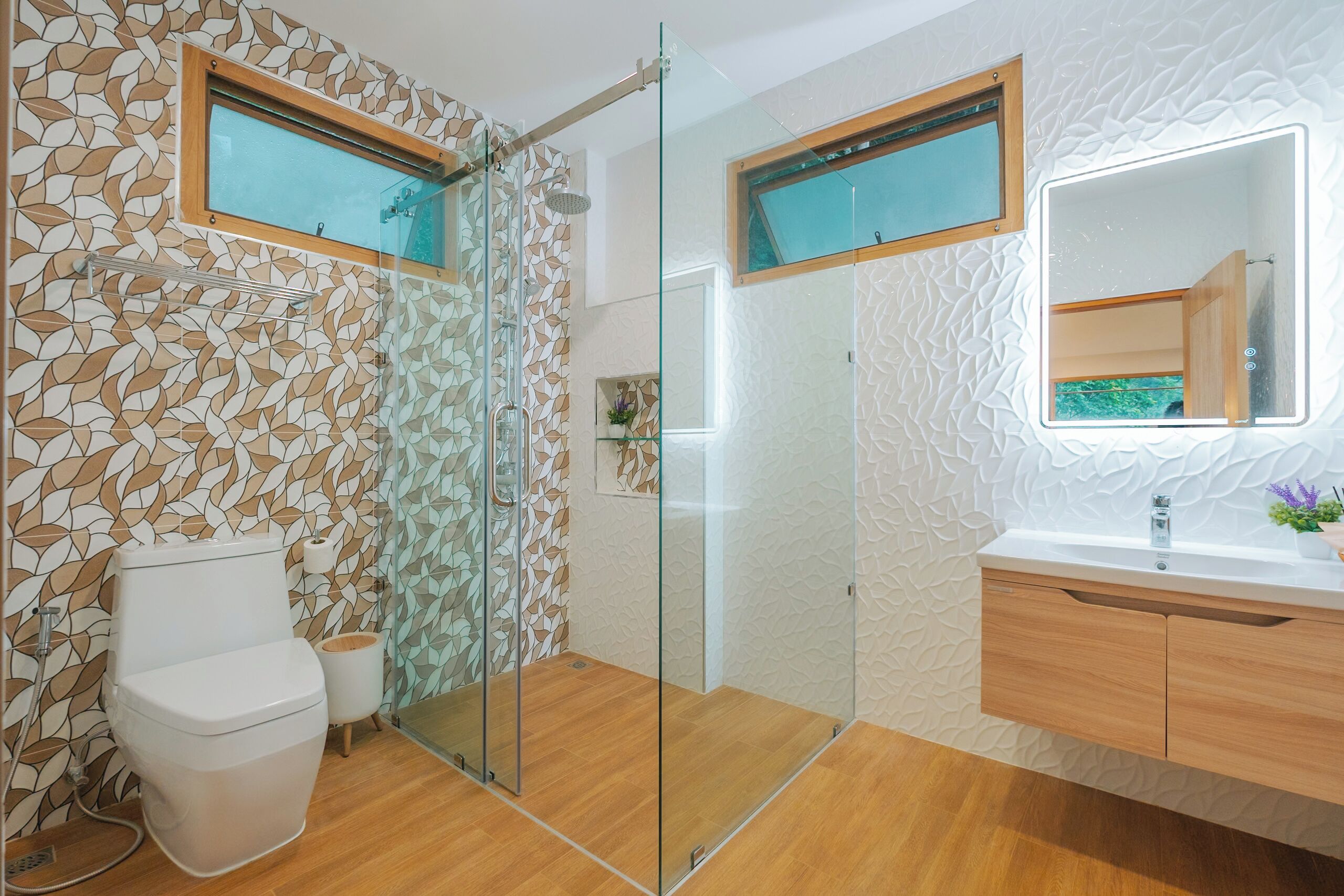A modern bathroom with a glass shower enclosure, a toilet, and a vanity with a mirror.