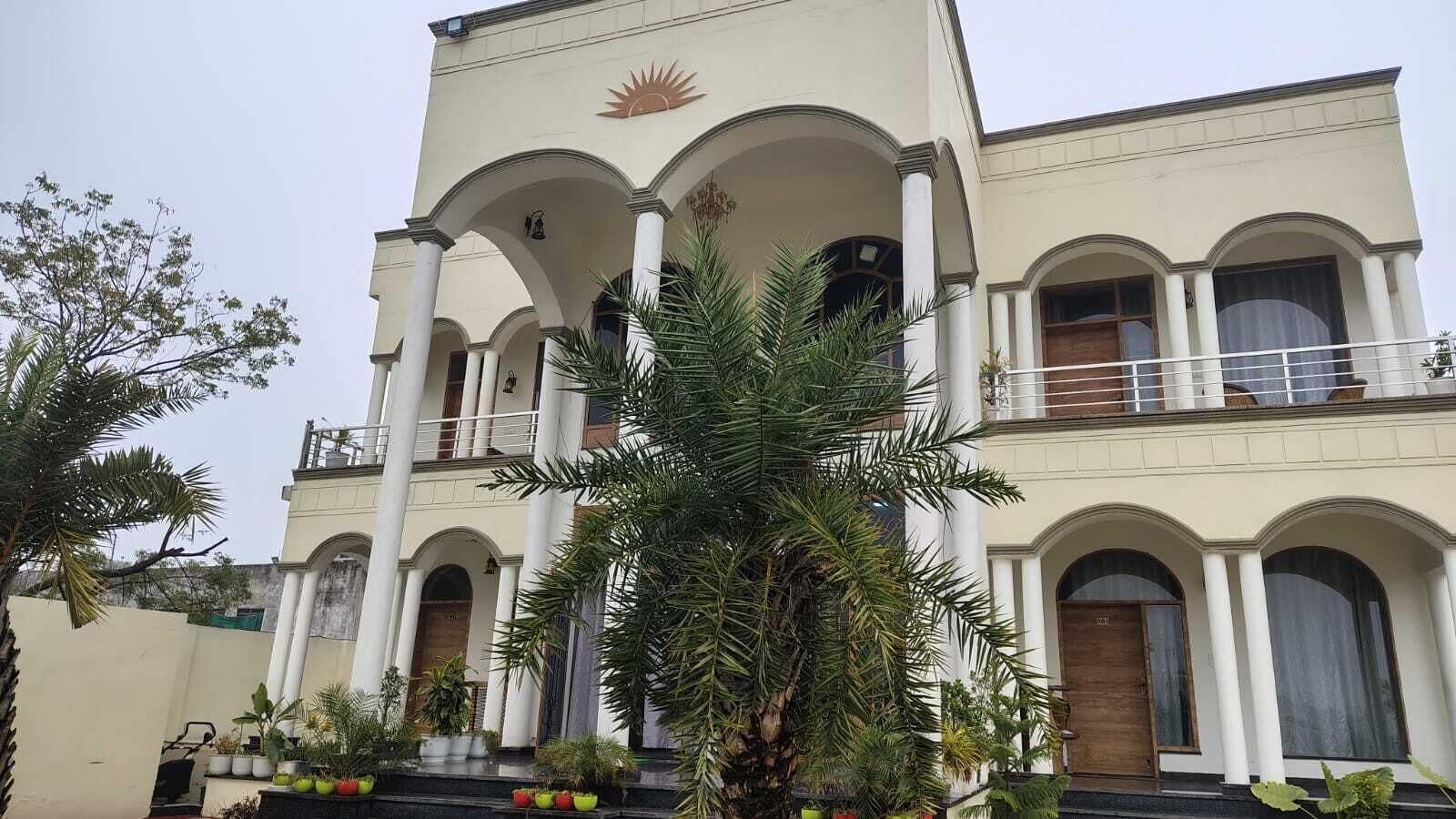 Un edificio de varios pisos con fachada simétrica, destacando una entrada central con escalinata, flanqueada por columnas y ventanas arqueadas.