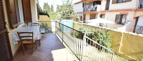 A balcony with a table and chairs, a railing, and a view of neighboring buildings.