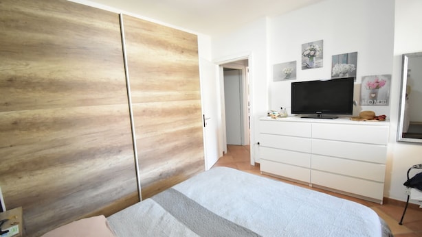 A bedroom with a bed, a wardrobe, a dresser, a television, and wall art. - APP.LIBECCIO - Appartamento LIBECCIO (Pula)