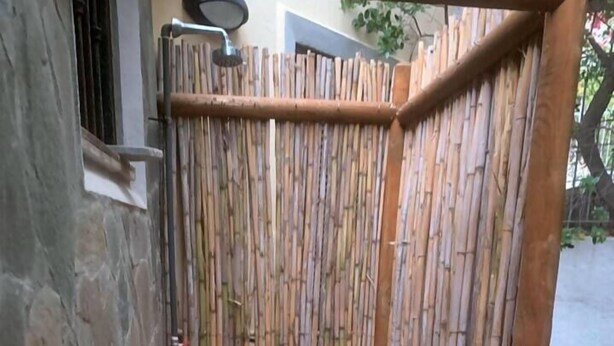 A bamboo fence with a shower area, stone wall, and tiled floor. - Casa Eden Roch - Villa Sole (Domus de Maria)