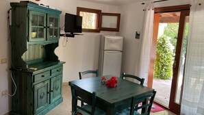 A dining area with a table, chairs, a cabinet, a television, and a refrigerator. - Casa Eden Roch - Villa Sole (Domus de Maria)