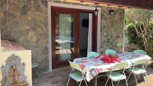 A stone building with a covered patio, a table with chairs, and a decorative fountain. - Casa Eden Roch - Villa Sole (Domus de Maria)