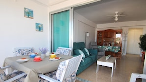 A dining area with a table set for two, a sofa, and a coffee table.