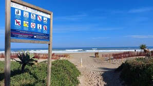 A beach sign with safety instructions and a clear view of the ocean.