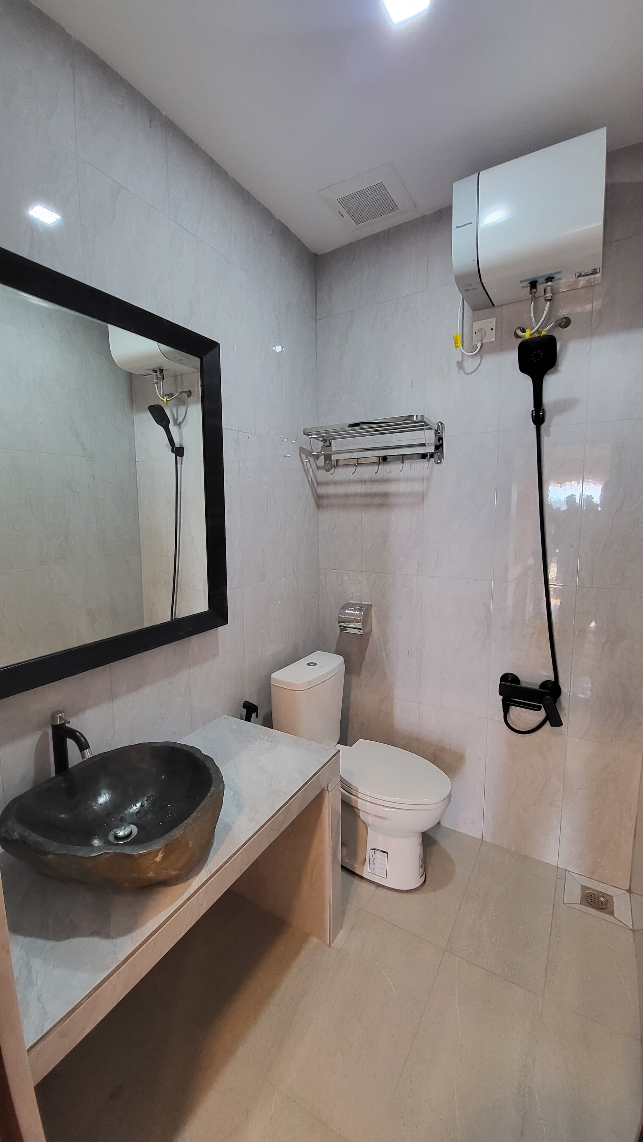 A bathroom with a large mirror, a sink, a toilet, and a shower.
