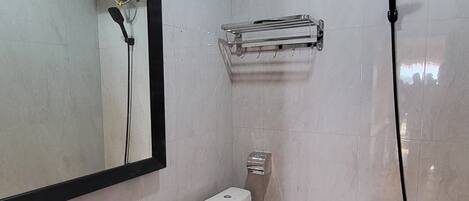 A bathroom with a large mirror, a sink, a toilet, and a shower.