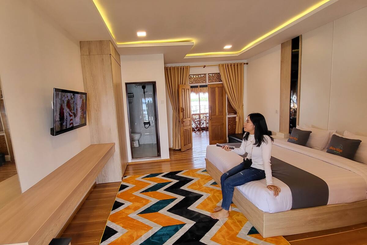 Een moderne woonkamer met een bank, een aan de muur bevestigde televisie en een kamerkleed met een patroon.