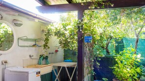 A compact laundry area with a washing machine, drying rack, and a small table. - Apartment with garden in Lacona, ideal for relax. (Capoliveri)