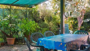 An outdoor patio with a table covered in a blue tablecloth, surrounded by chairs. - Apartment with garden in Lacona, ideal for relax. (Capoliveri)