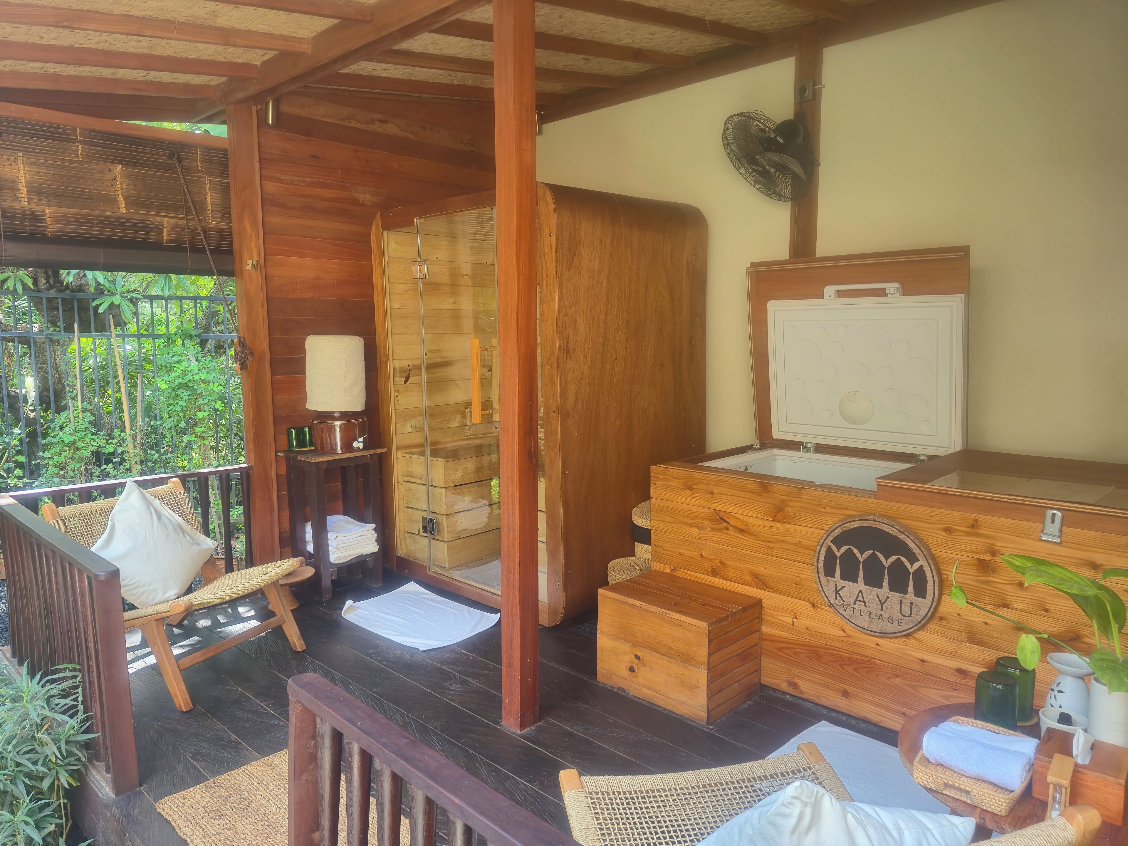 A wooden cabin with a wooden bench, a small table with a towel, and a wooden chest of drawers.