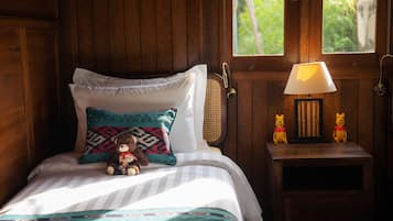Ein Zimmer mit Holzwänden, einem Bett, einer Nachttischlampe und zwei Teddybären auf einem Nachttisch.