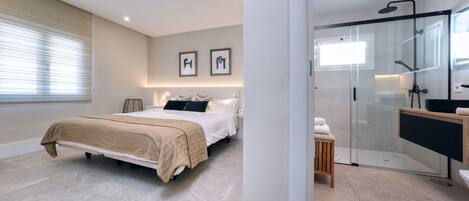 A modern bedroom with a bed, bedside tables, and a large window with blinds.