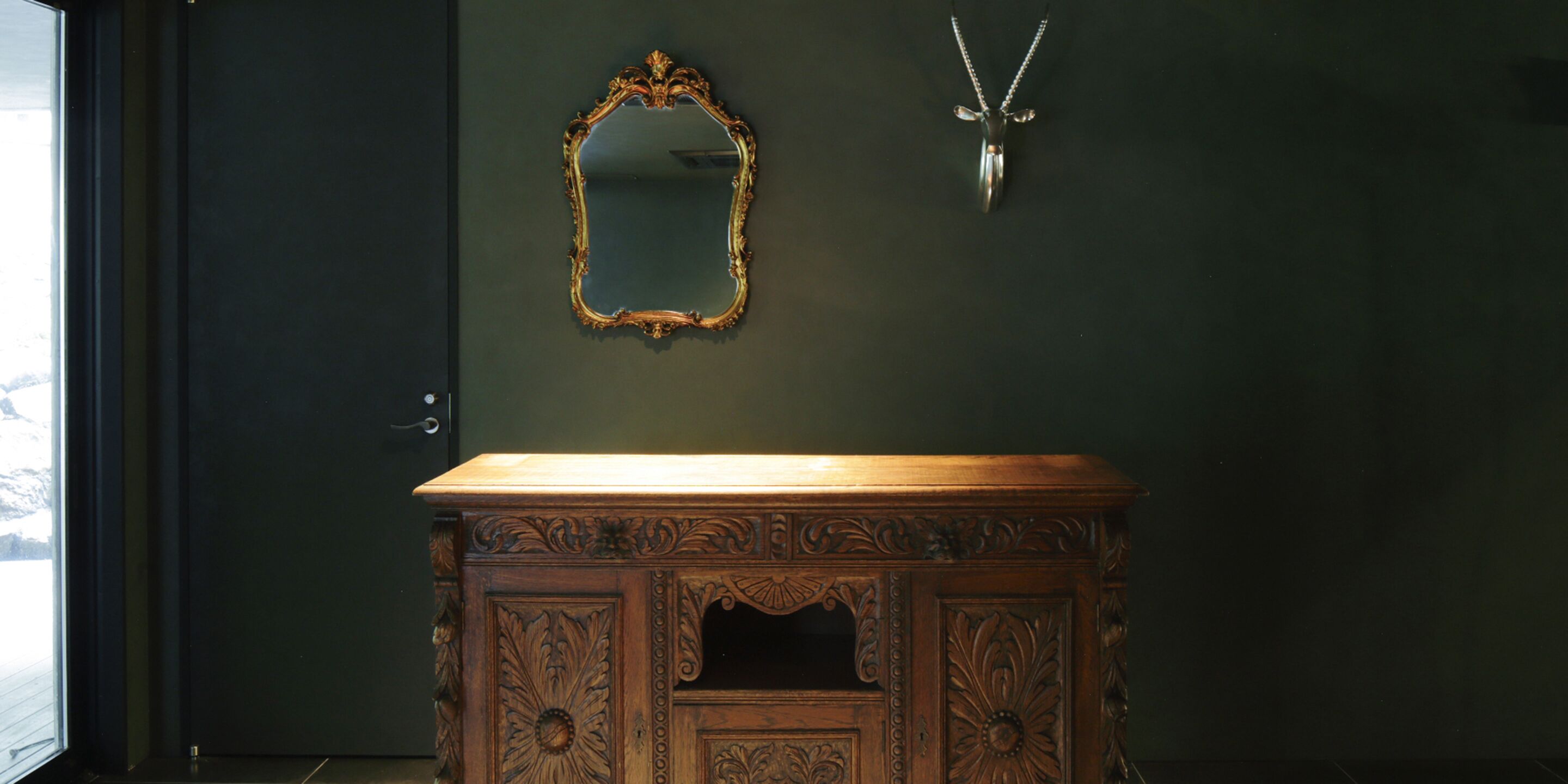 A bathroom with a wooden vanity, a mirror, and a wall-mounted light fixture.
