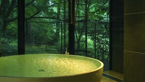 Una bañera grande con vistas a un bosque a través de un recinto de vidrio.