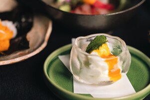Un postre en un bol de vidrio sobre un plato verde con una servilleta debajo.