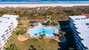An aerial view of a resort with a central swimming pool, multiple balconies, and a beach view. - Stunning Ocean Views, Beachfront Pool, Heated Indoor Pool, Hot Tub, Family Condo, Tennis, Gym, Sauna (St. Augustine)